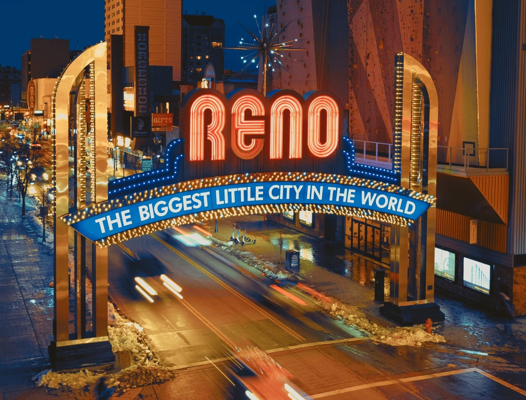 The illuminated Reno Arch reading Reno, The Biggest Little City in the World, over downtown Reno at night